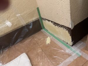 巾木の補修箇所にパテが施され、既存の塗装色に合わせて部分塗りされている途中の状態。