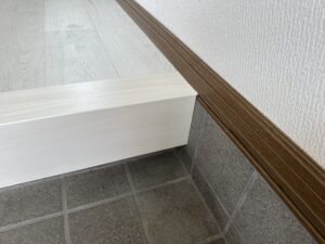 上がり框右端の納まり、白木とブラウン巾木との調和
