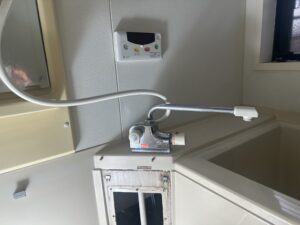 浴室内の古いシャワー水栓。壁に設置され、ホースがつながれている。