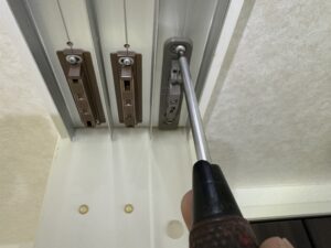 引き戸の上部ストッパー部分をドライバーで微調整している様子