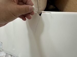 割れたエプロンの破片を手に持ち、ダメージの大きさを確認している