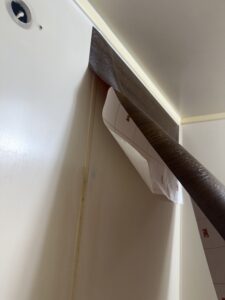 浴室の壁に貼るダイノックシートの貼り始め。下地を整え、丁寧に空気を抜きながら施工する様子