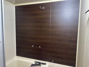 ダークブラウンの木目柄ダイノックシートを貼り終えたユニットバス。ビジネスホテルのような高級感ある仕上がり