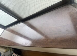 白濁シミが浮いた窓際木部カウンターの施工前写真